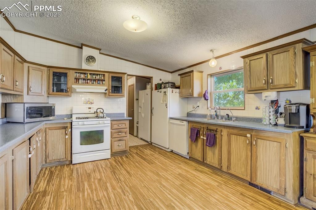 Image 13 of 50: Kitchen featuring crown molding, a textured ceiling, white appliances, ligh