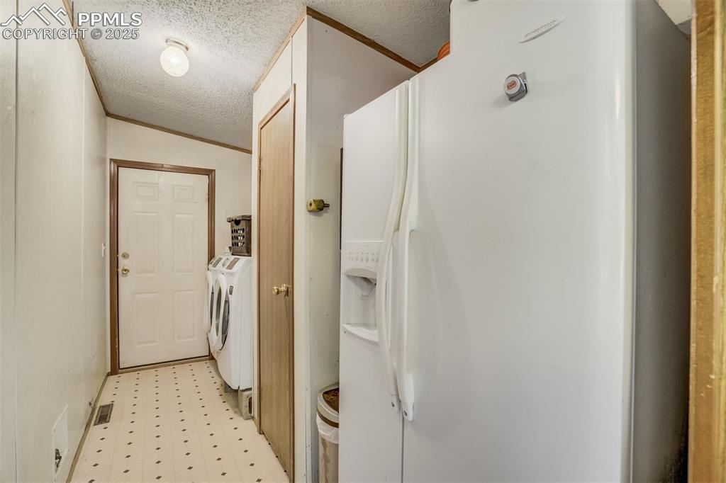 Image 14 of 50: Washroom with independent washer and dryer, light floors, and a textured ce