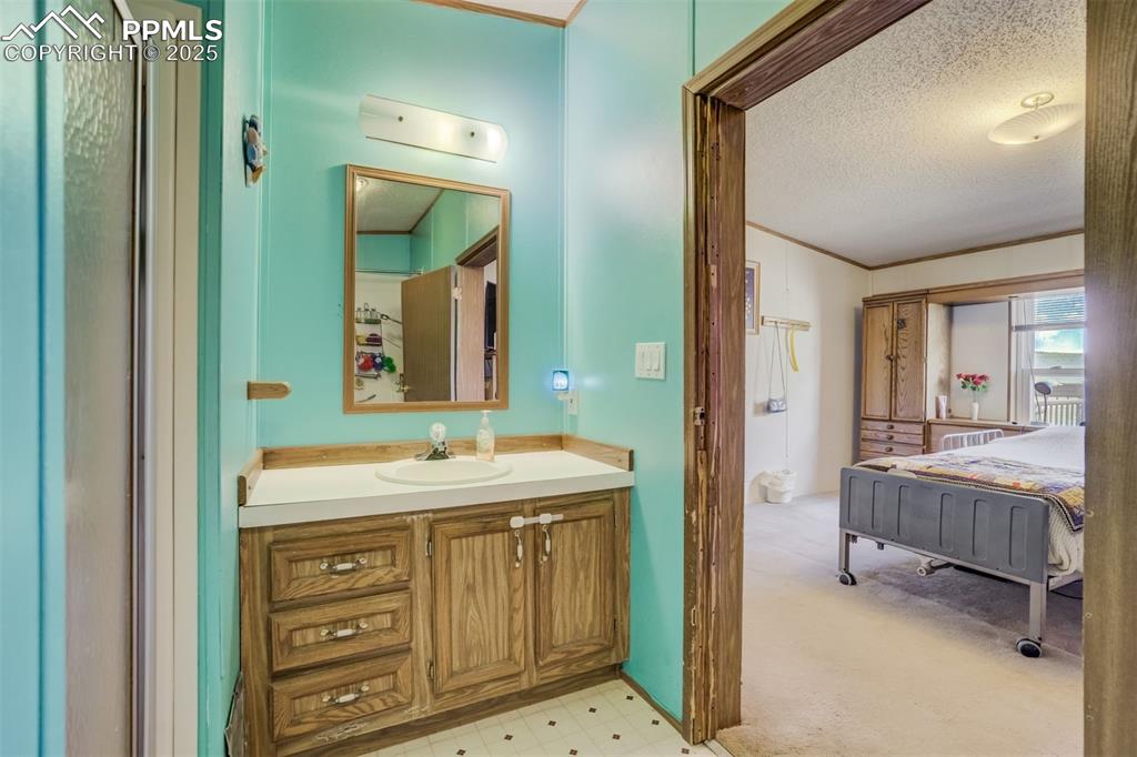 Image 20 of 50: Bathroom with vanity, a textured ceiling, tile patterned floors, and crown 