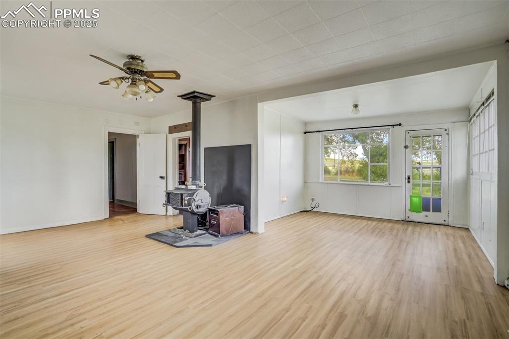 Image 31 of 50: Unfurnished living room with a wood stove, wood finished floors, and a ceil