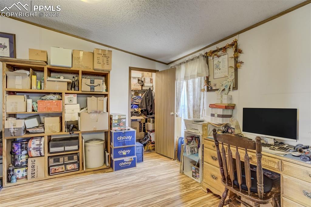 Image 8 of 50: Office area with crown molding, wood finished floors, and a textured ceilin