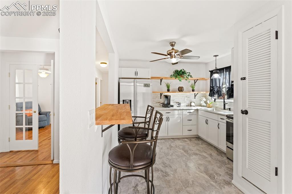 Image 14 of 50: Kitchen with open shelves, white cabinets, decorative backsplash, stainless