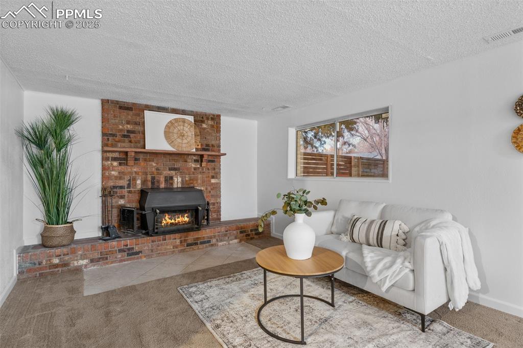 Image 18 of 28: Large open family room with wood fireplace and lots of natural light