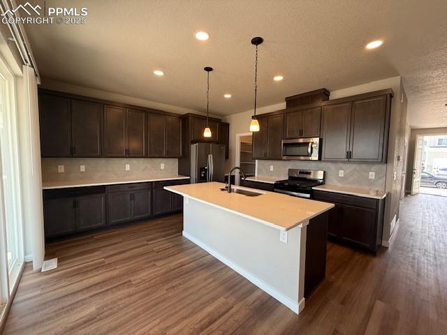 Image 2 of 11: Kitchen featuring a textured ceiling, stainless steel appliances, dark brow