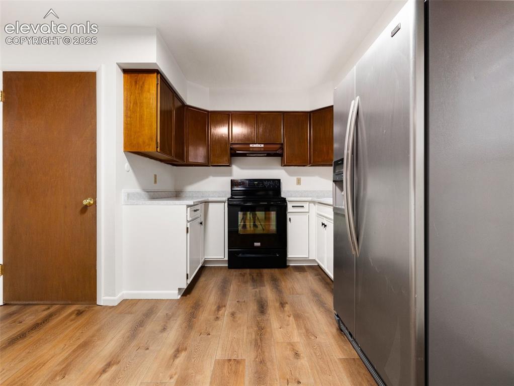 Image 10 of 34: Wood-finish flooring with white base cabinetry, complemented by dark wood u