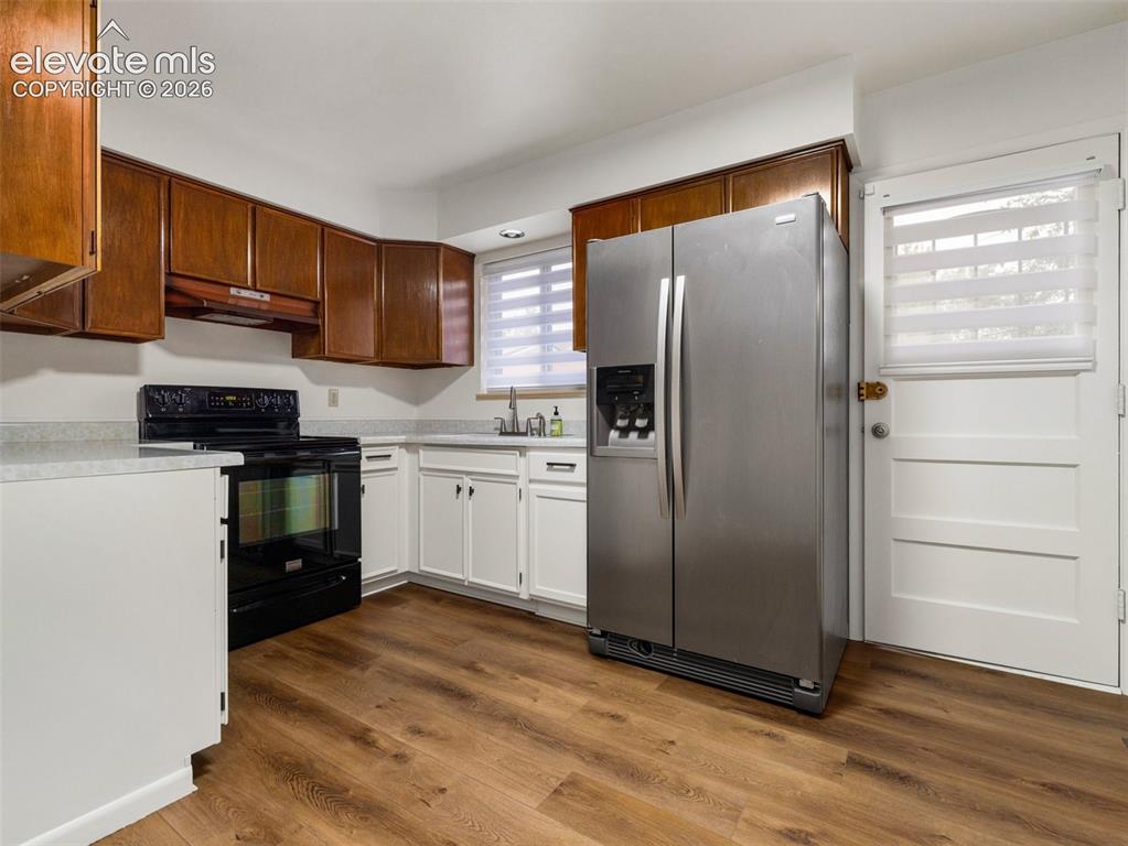 Image 11 of 34: Kitchen featuring wood-finish flooring, white lower cabinetry, wood upper c