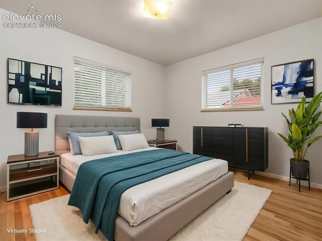 Image 12 of 34: Hardwood-finish flooring, white walls, and two windows with blinds