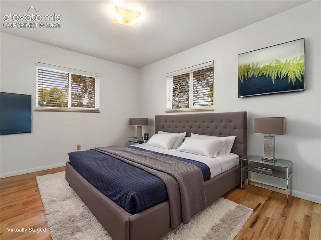 Image 15 of 34: Hardwood flooring, two windows with blinds, recessed ceiling light, and a b