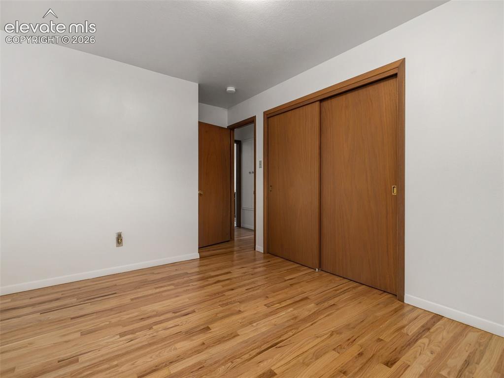 Image 17 of 34: Hardwood flooring, white painted walls, wood-finish sliding closet doors, a