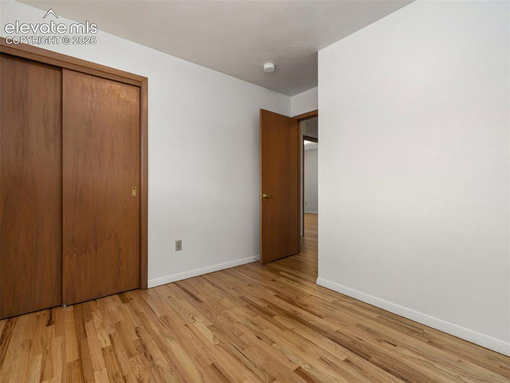 Image 21 of 34: Wood-finish flooring throughout, white walls, and a sliding door closet wit