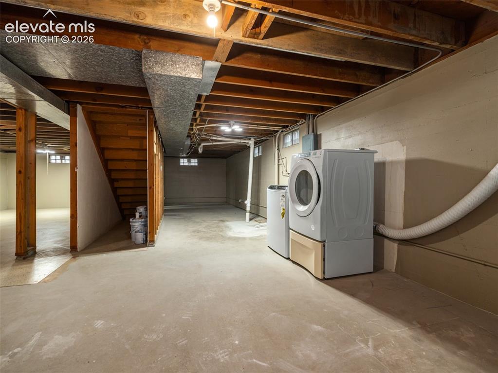 Image 23 of 34: Unfinished basement with concrete flooring, exposed wood beam ceiling, full