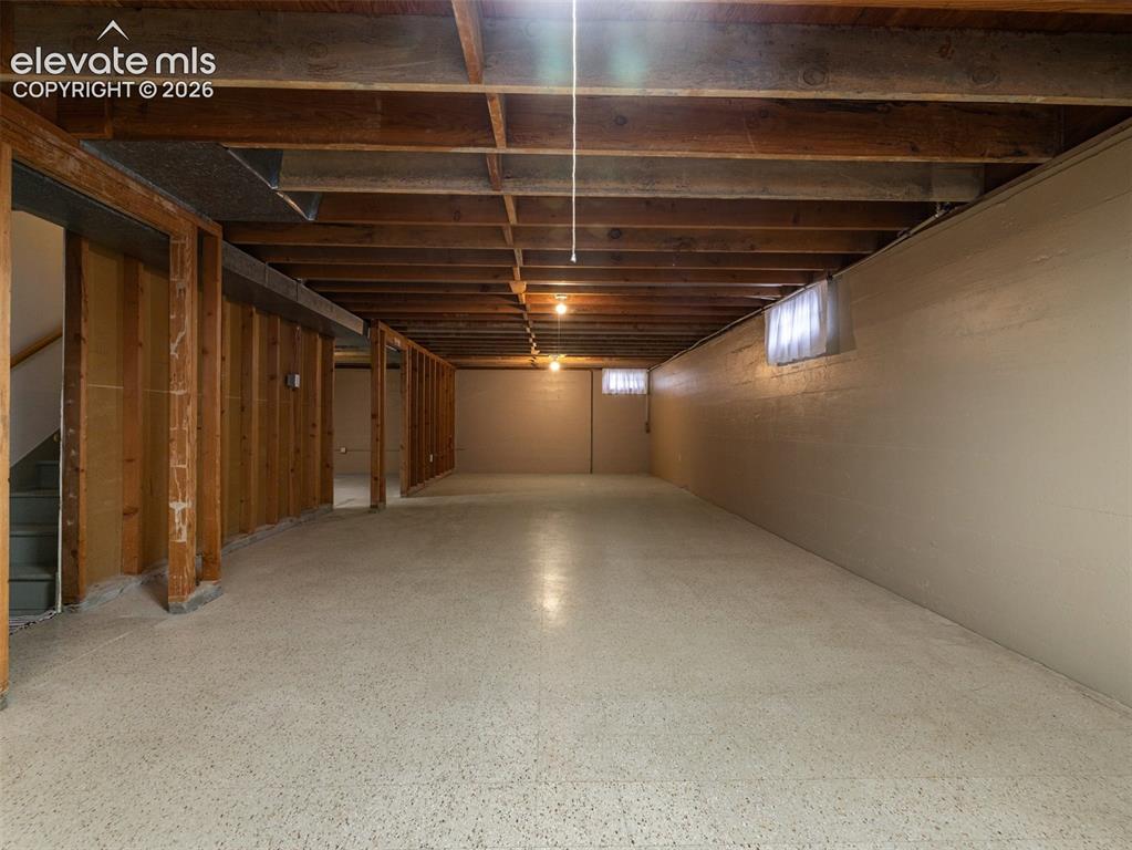 Image 25 of 34: Unfinished basement featuring exposed wood joists, concrete flooring, and m