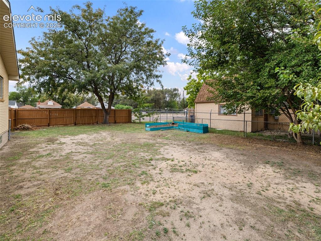 Image 29 of 34: Expansive rear yard with a wood privacy fence and mature trees