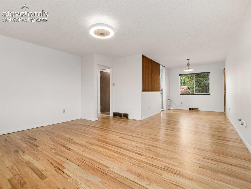 Image 6 of 34: Wood-finish flooring, white walls, and a wood-slat partition