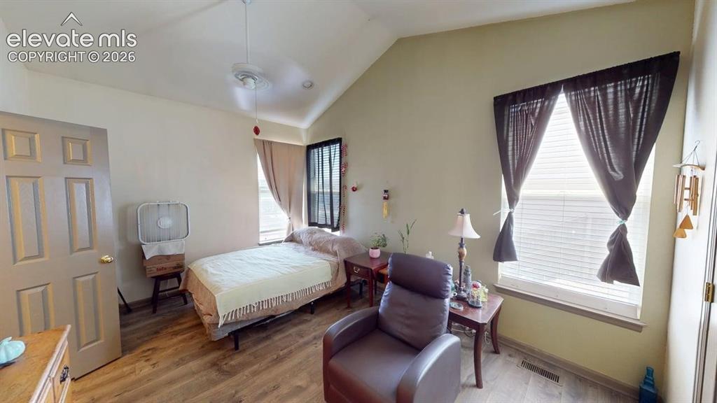 Image 14 of 20: Vaulted ceiling room featuring wood-finish flooring, two windows with blind