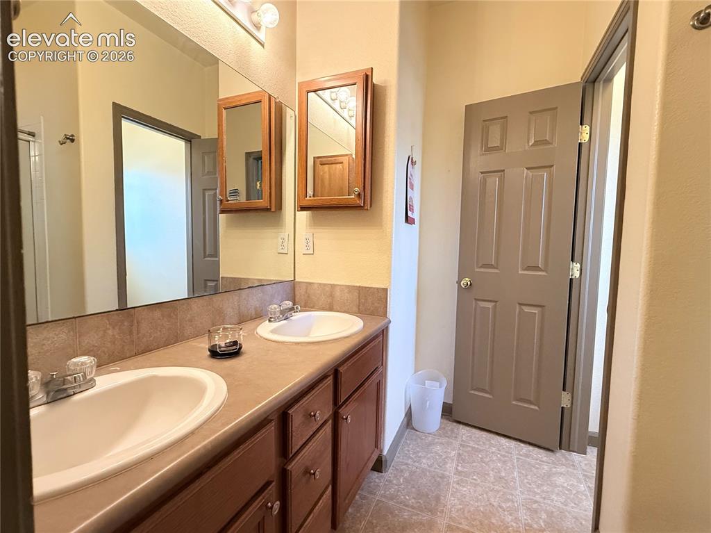 Image 19 of 20: Double vanity with individual sinks, wood-finish cabinetry, and laminate co