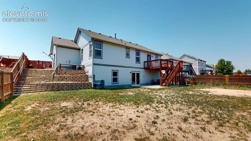 Image 5 of 20: Rear exterior featuring a multi-level wood deck, ground-level patio, and sl