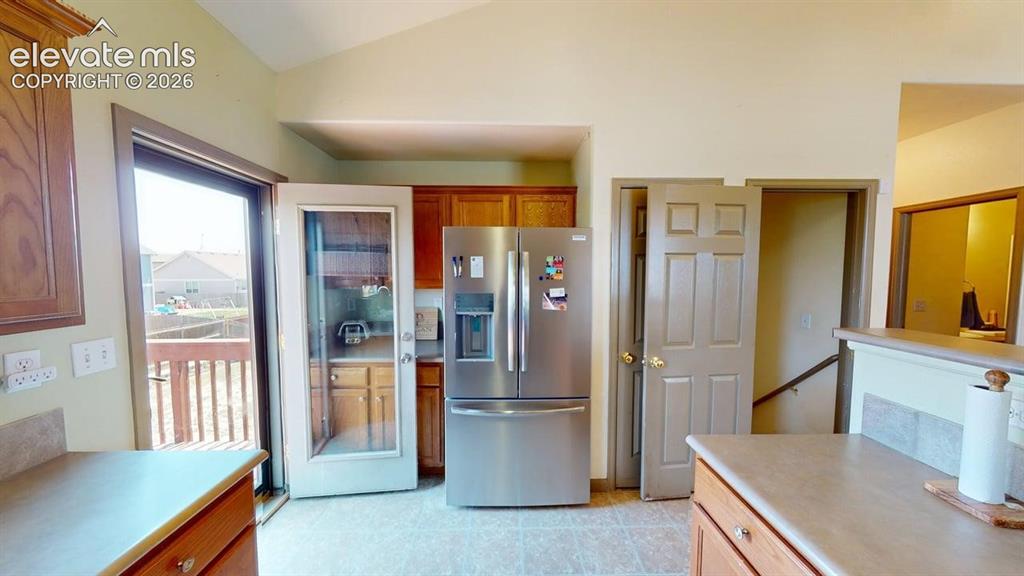 Image 7 of 20: Kitchen area featuring a stainless steel refrigerator, wood cabinetry, and