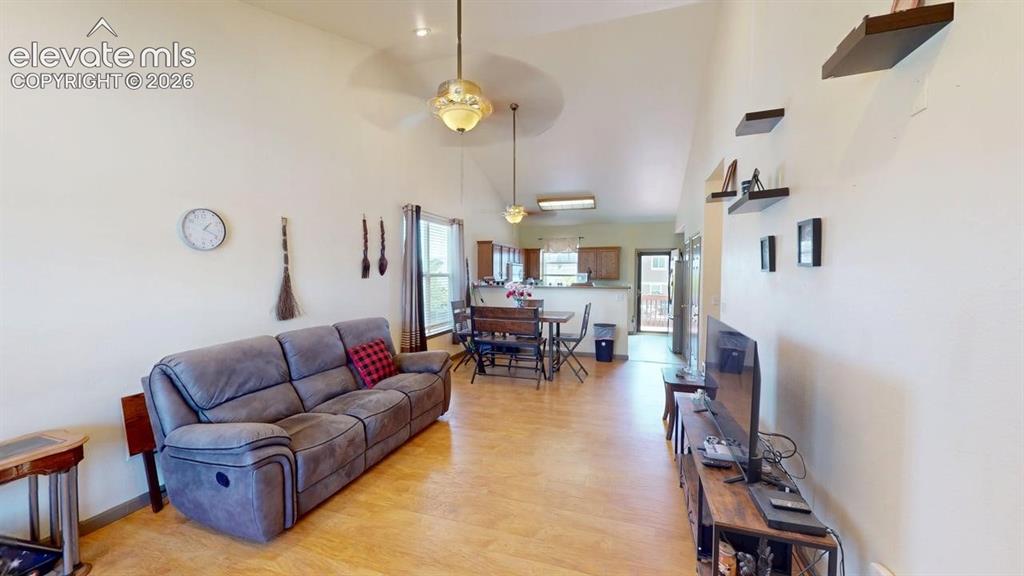 Image 9 of 20: Open-concept living area with vaulted ceilings, wood-finish flooring, and a