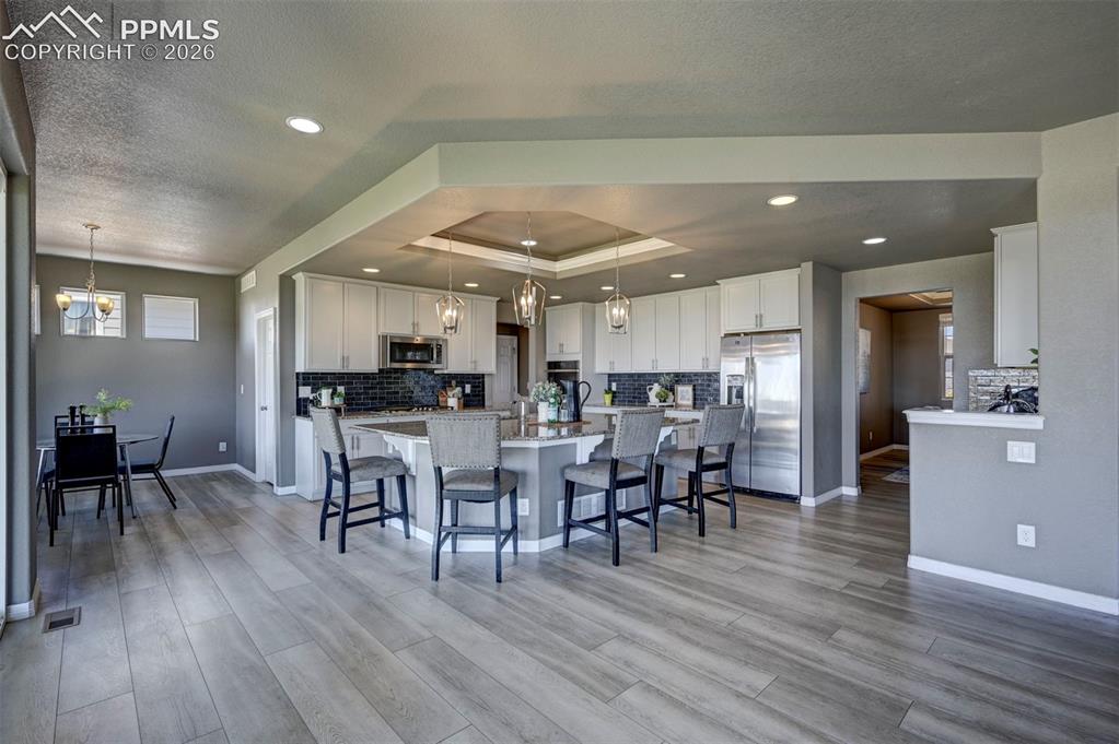 Image 12 of 50: Open-concept kitchen and dining area featuring light wood-finish flooring, 