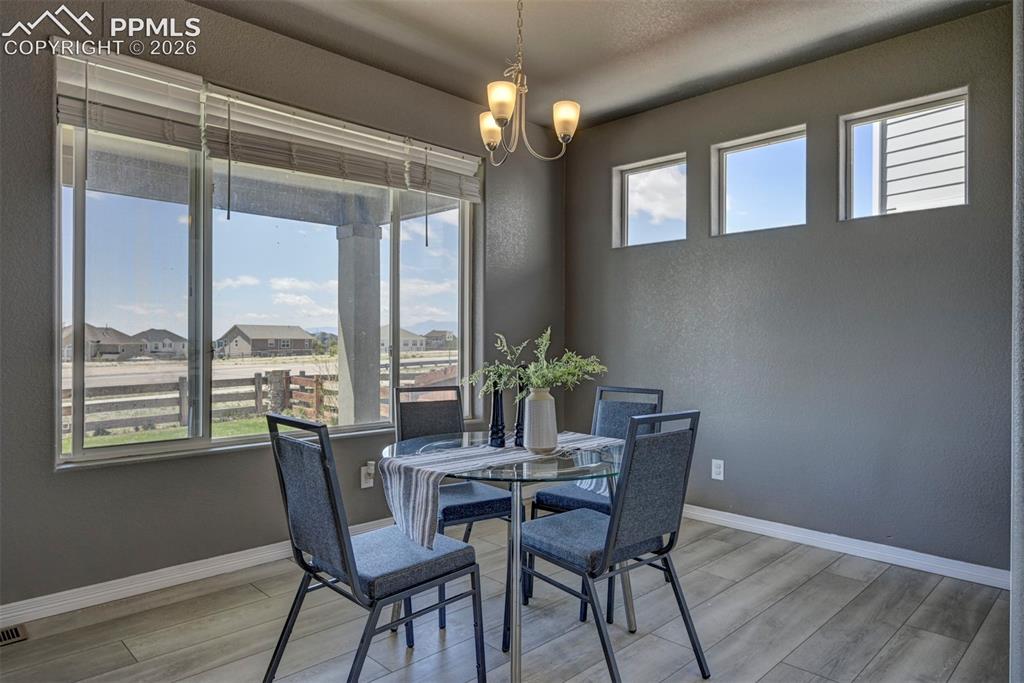 Image 15 of 50: Dining area featuring wood-finish flooring, a large window with blinds, thr