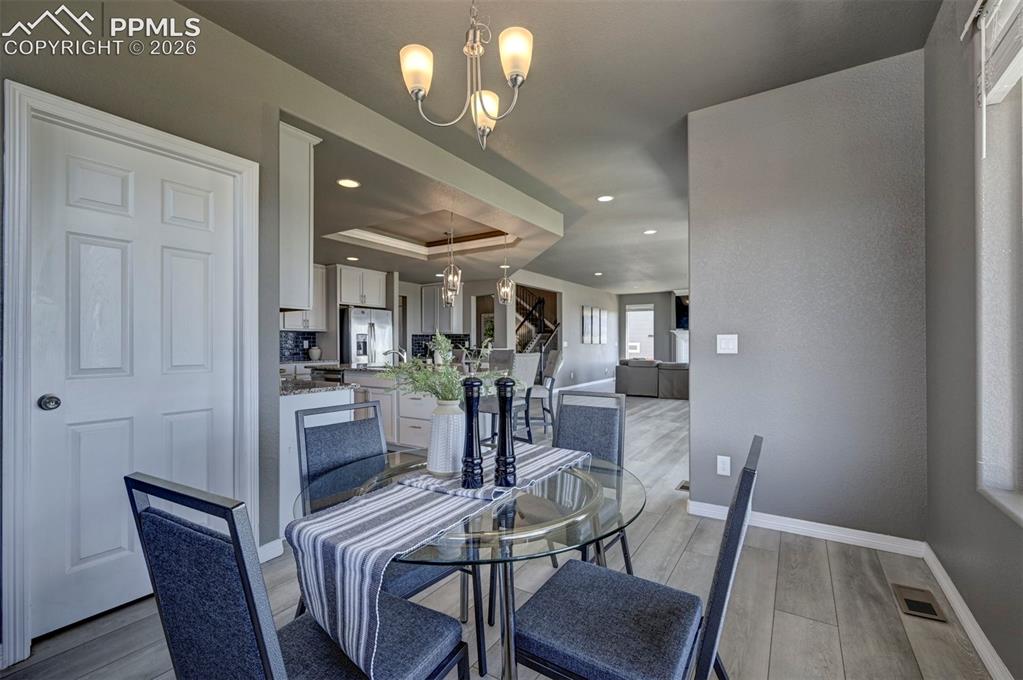 Image 16 of 50: Dining area featuring wood-finish flooring, a contemporary chandelier, and 