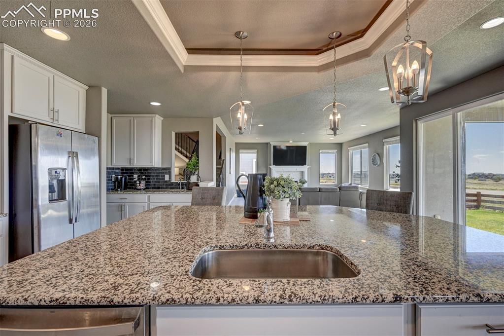 Image 17 of 50: Spacious kitchen island featuring a stainless steel undermount sink and gra