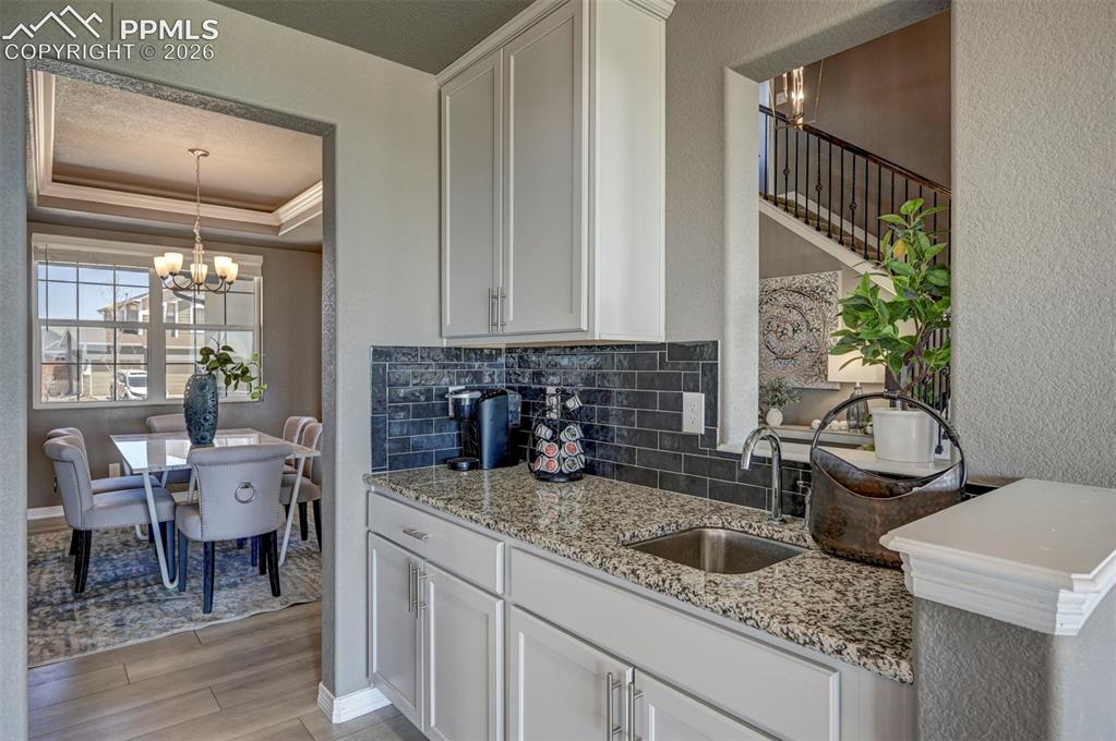 Image 19 of 50: Built-in wet bar featuring a stainless steel sink, granite-patterned counte