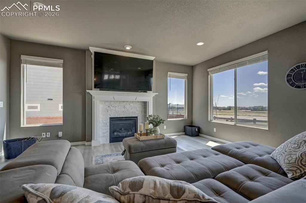 Image 21 of 50: Living area featuring a fireplace with a white mantel and stone surround, r