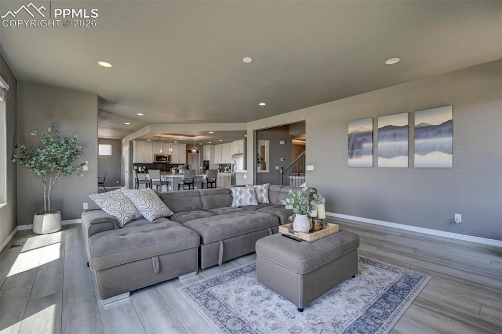 Image 23 of 50: Spacious living area featuring light wood-finish flooring, recessed lightin
