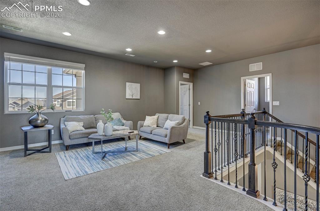 Image 27 of 50: Carpeted upper-level landing featuring a large window with blinds, recessed