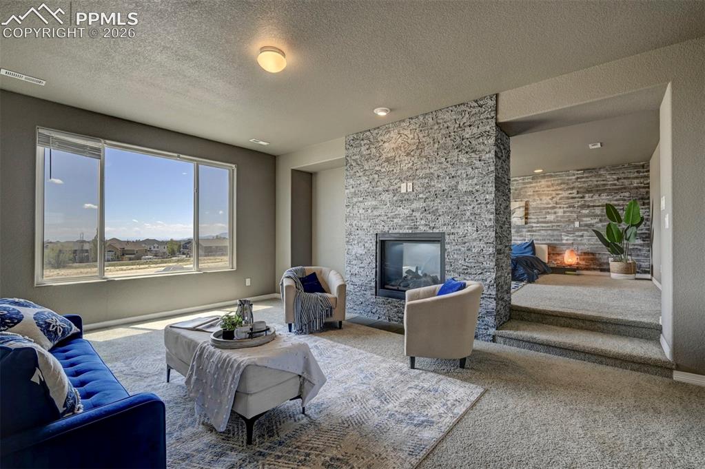 Image 29 of 50: Living area featuring a stone accent wall with a built-in fireplace, large 