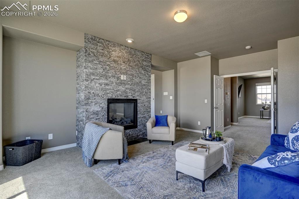 Image 30 of 50: Living area featuring a floor-to-ceiling stone-faced fireplace with a black