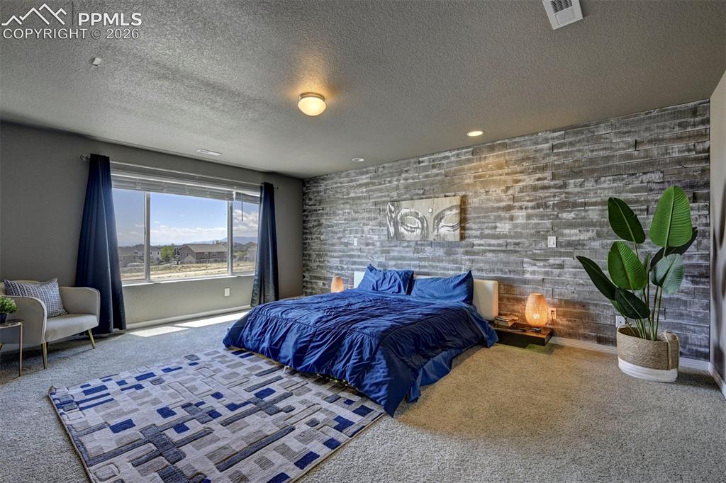 Image 32 of 50: Spacious room featuring a textured accent wall, overhead lighting, and wall