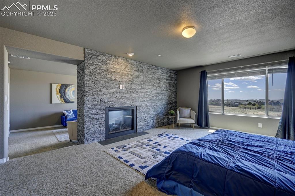 Image 33 of 50: Spacious room featuring a stone-clad fireplace and a large picture window