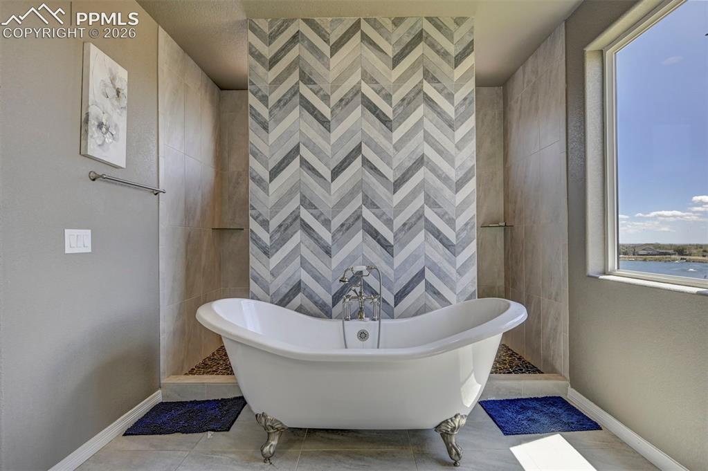 Image 37 of 50: Freestanding clawfoot tub with a chevron-patterned accent wall, flanked by 