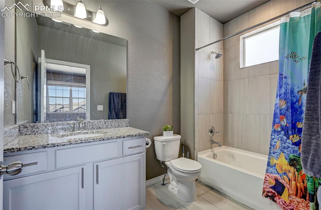 Image 40 of 50: Bathroom featuring a white vanity with a speckled countertop and a rectangu