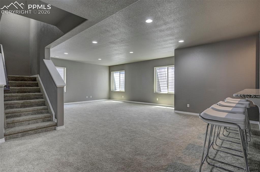 Image 42 of 50: Spacious carpeted room featuring recessed lighting, multiple windows with b