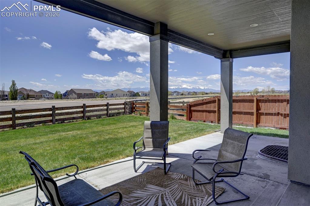 Image 46 of 50: Covered concrete patio with recessed lighting, offering an expansive grassy