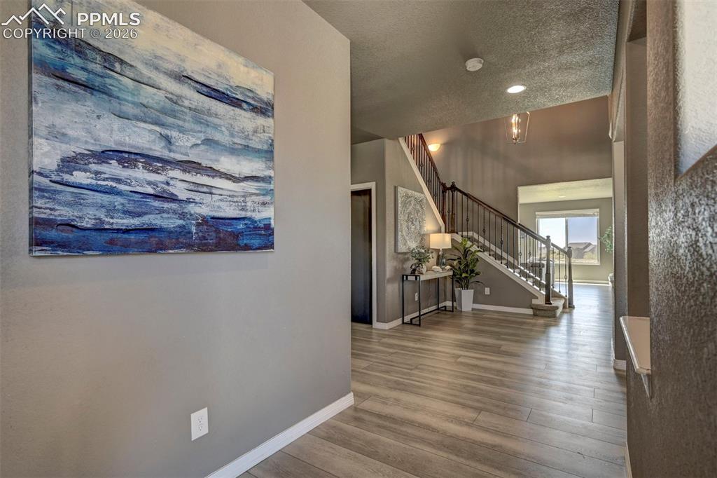 Image 5 of 50: Foyer featuring wood-finish flooring, a two-story ceiling, black metal stai