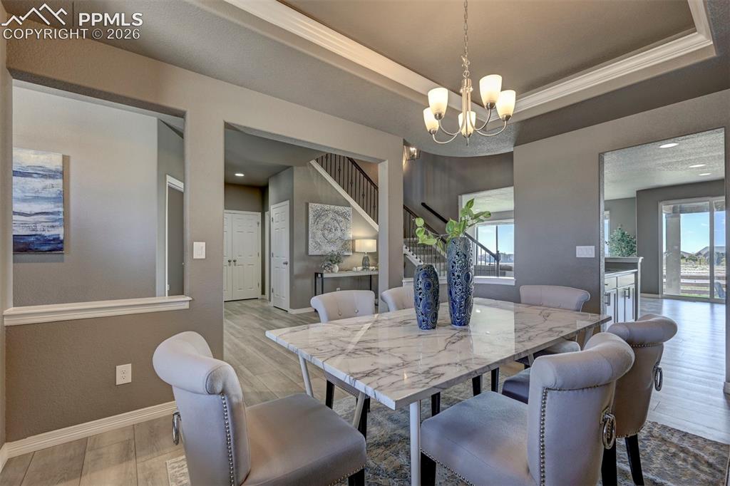 Image 9 of 50: Dining area featuring a marble-finish tabletop, coffered ceiling with crown