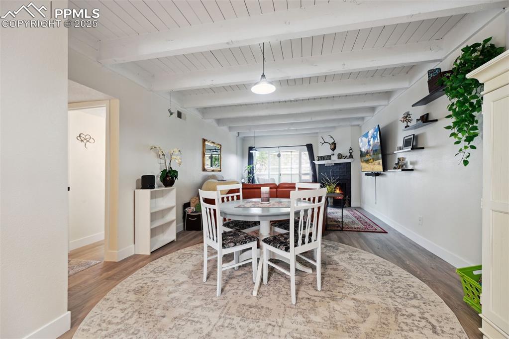Image 11 of 16: Dining room featuring wood finished floors, a warm lit fireplace, and a woo