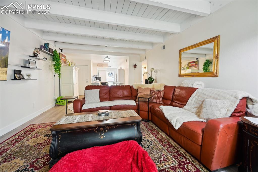Image 13 of 16: Living room with wood finished floors and a wood ceiling with exposed beams