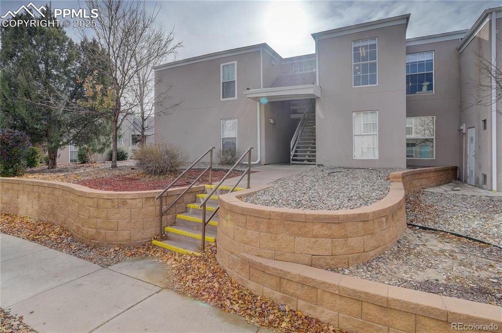 Image 16 of 16: Rear view of property with stairs and stucco siding
