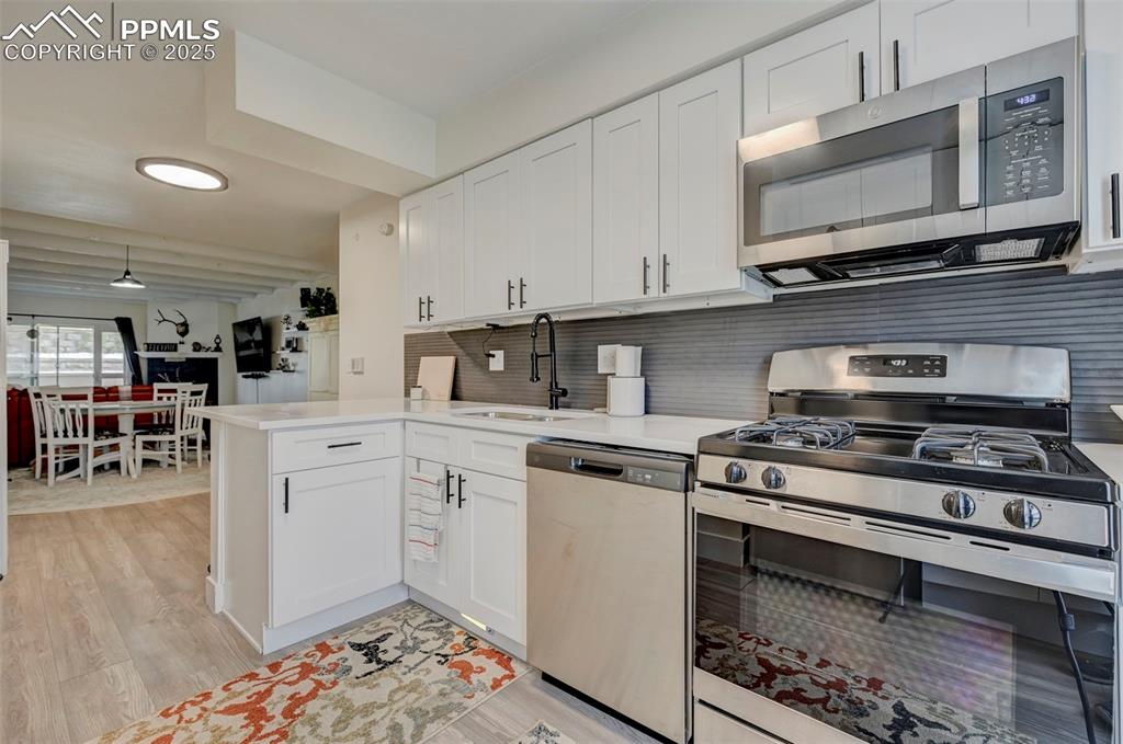 Image 3 of 16: Kitchen with stainless steel appliances, light countertops, white cabinetry