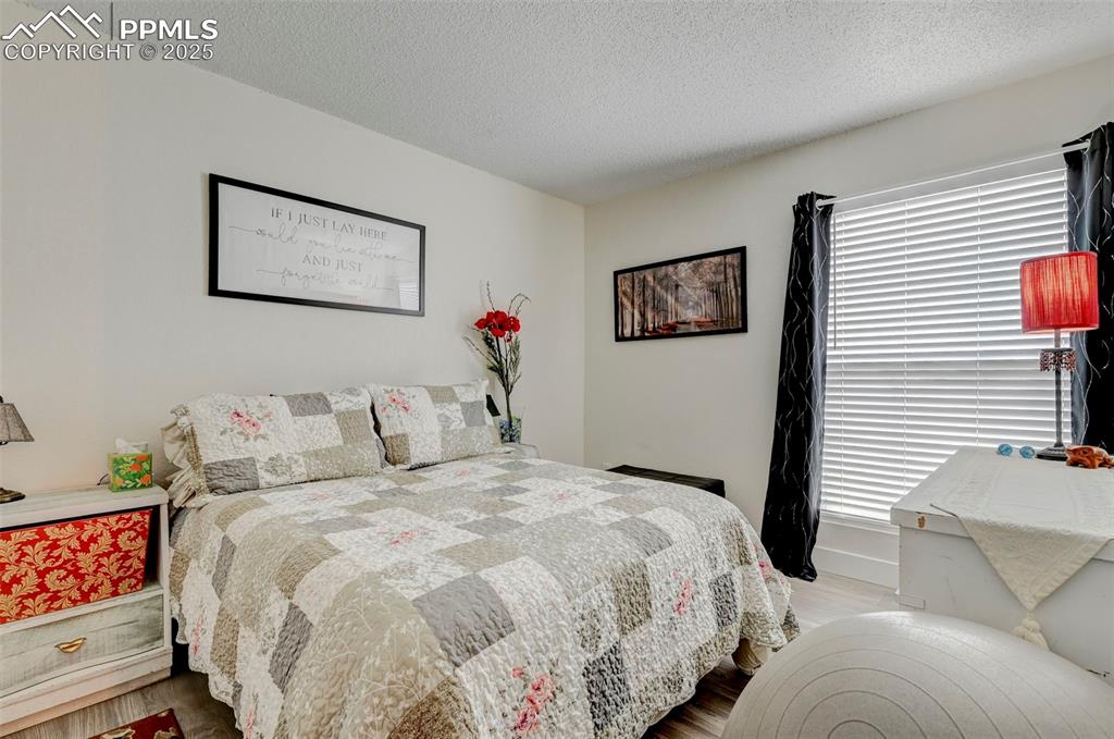 Image 8 of 16: Bedroom with multiple windows, wood finished floors, and a textured ceiling