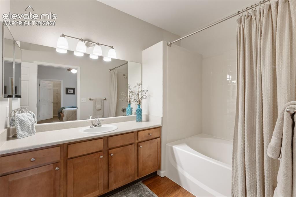 Image 15 of 31: Double vanity with a single basin sink, warm wood-finish cabinetry, and an 