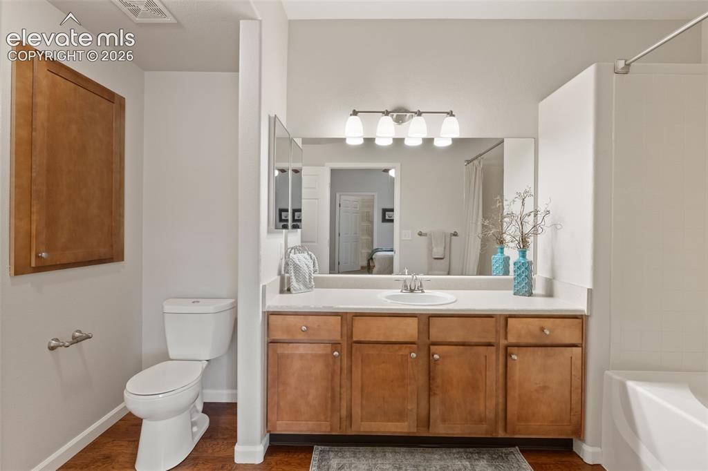 Image 16 of 31: Bathroom featuring a vanity with wood-finish cabinetry, a white countertop,
