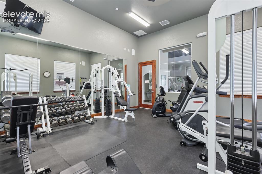 Image 23 of 31: Fitness center featuring rubber flooring, a mirrored wall, and a wood-finis