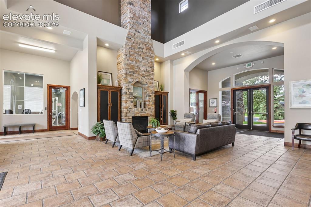 Image 25 of 31: Spacious common area featuring a stone fireplace, arched doorways, tiled fl